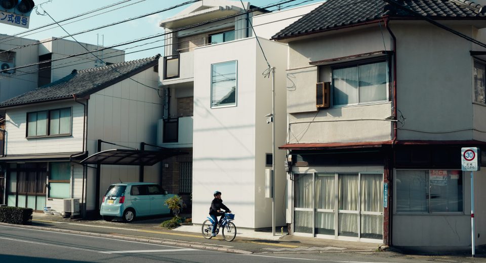 Exterior view of O-Studio showing three simple timber-clad volumes in a small residential neighbourhood.