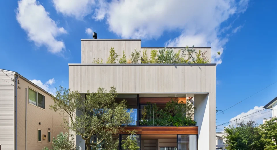 Exterior day view of House F by Kamakura Studio showing a two level structure with open sliding panels that connect the ground floor to the street and create a shared community space.